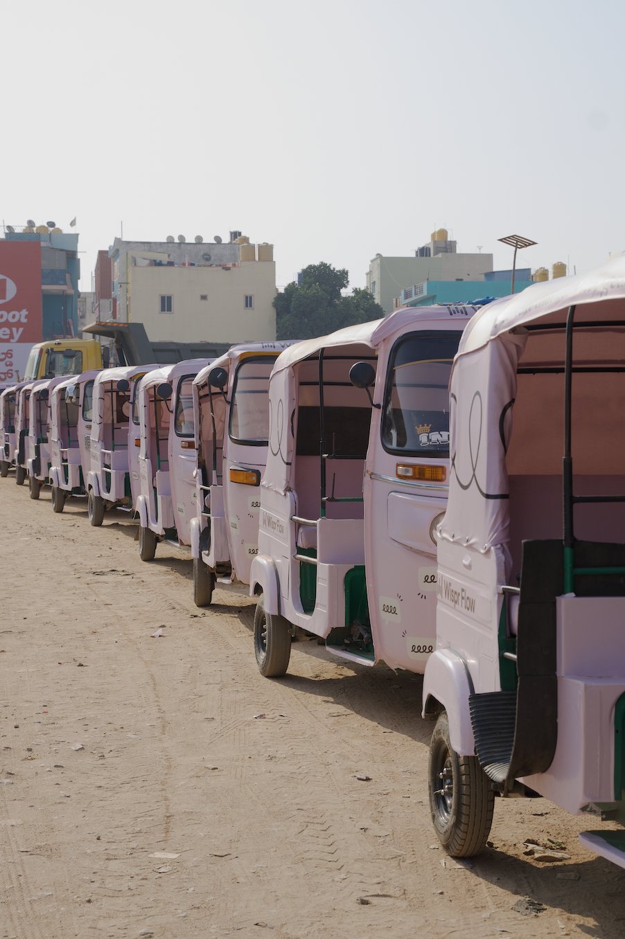 A row of branded auto-rickshaws driving through Bengaluru
